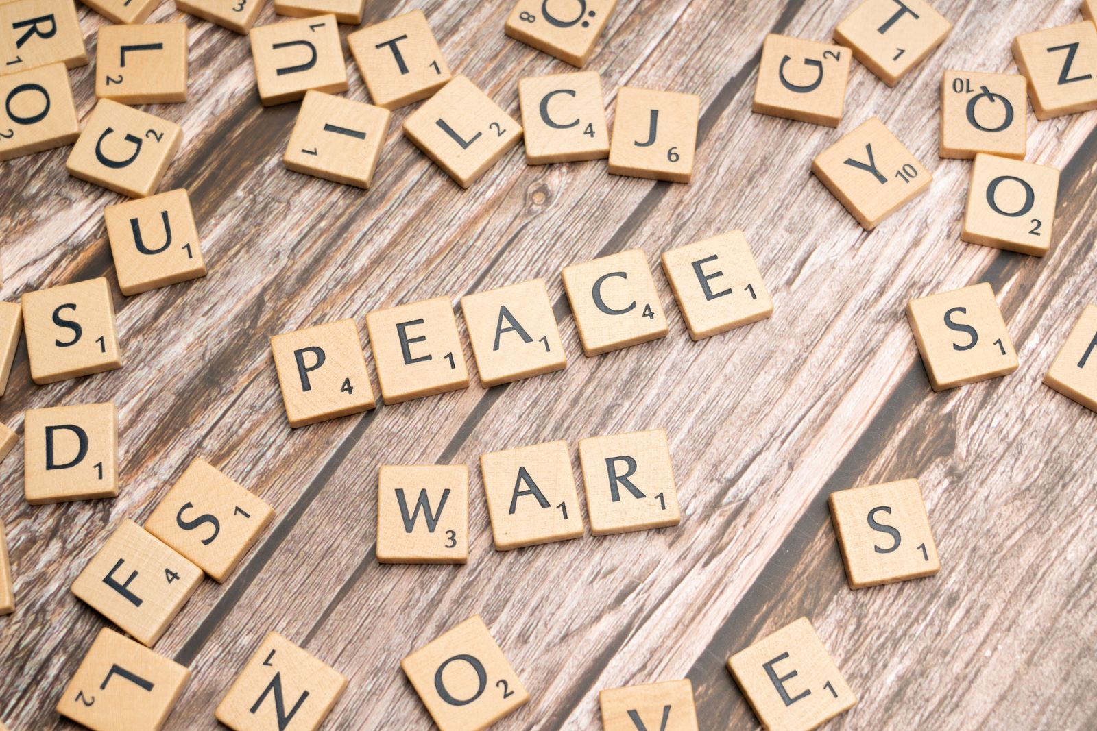 Letter tiles spelling peace and war, symbolising dialogue and diplomacy