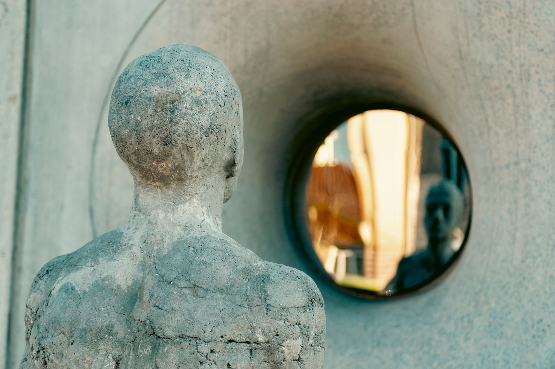 Sculpture facing a circular window, evoking contemplation and perspective